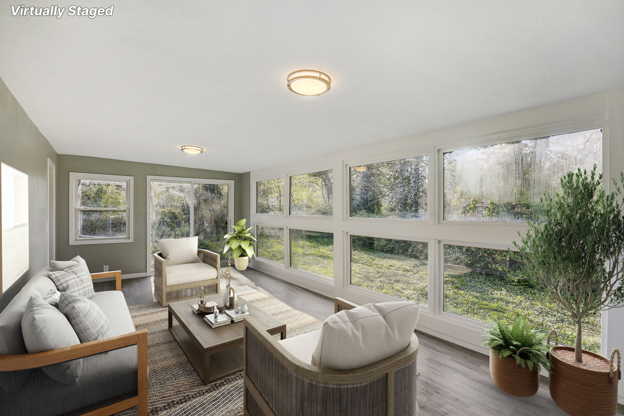 Bright sunroom with large windows, modern wood-accented furniture, and lush green outdoor views.